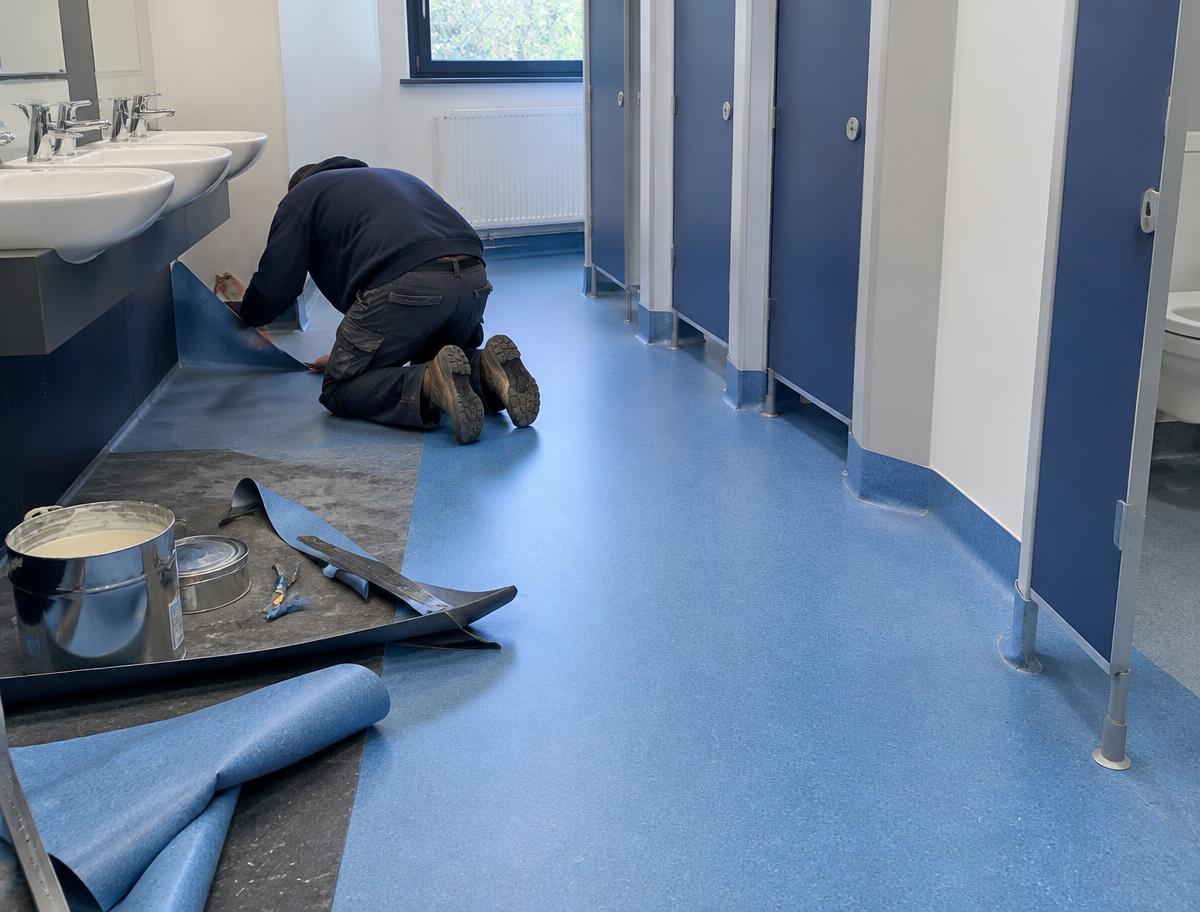 Safety vinyl flooring being fitted in a school washroom